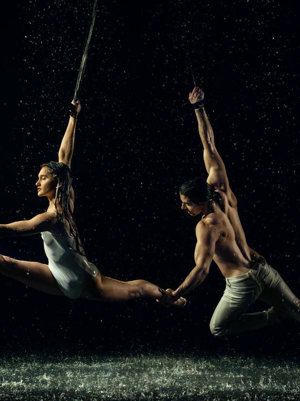 Woman performing a controlled, graceful movement in a dark studio.